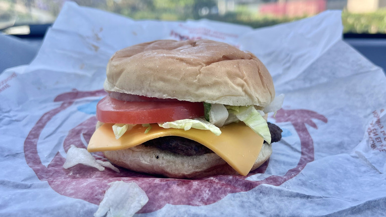 Side view of a Wendy's Jr. Cheeseburger Deluxe with a paper wrapper