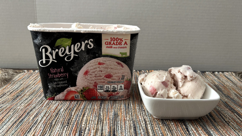 Breyers strawberry ice cream in carton and bowl on neutral placemat