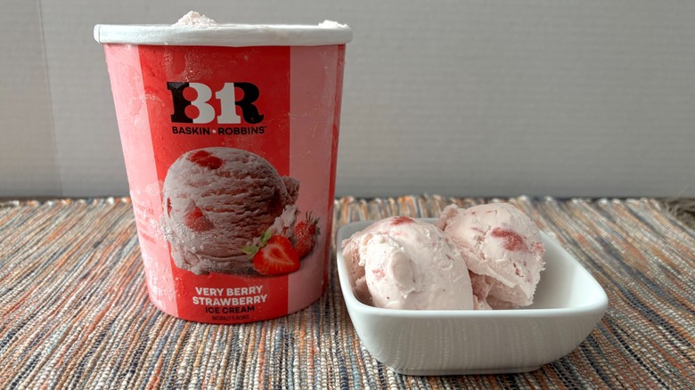 Baskin Robbins strawberry ice cream in carton and bowl on neutral placemat