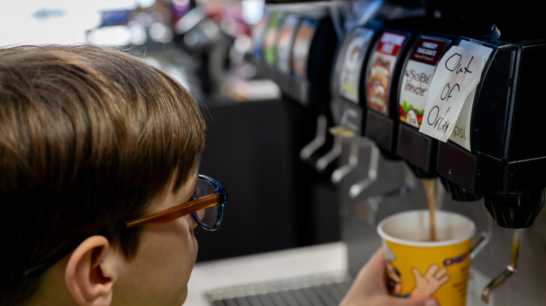 A child filling a drink from a soda fountain machine