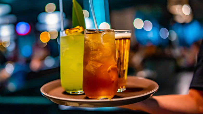 Bartender serving tray of cocktails