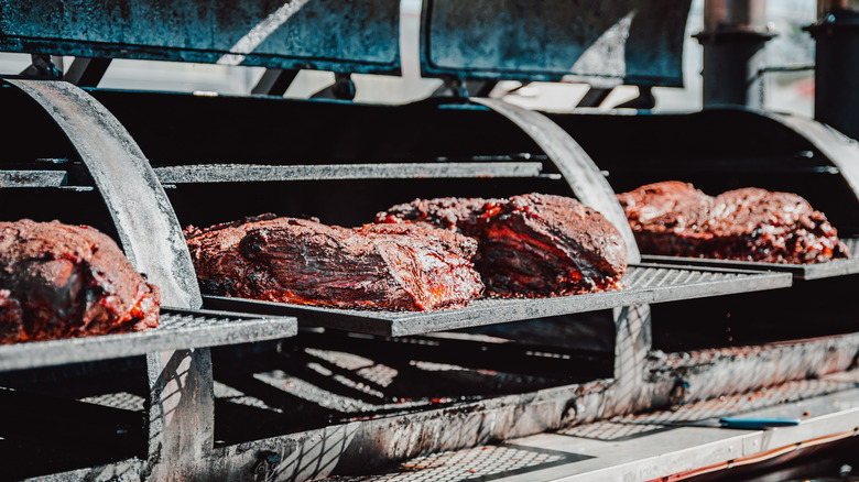 Four briskets sit in a large smoker