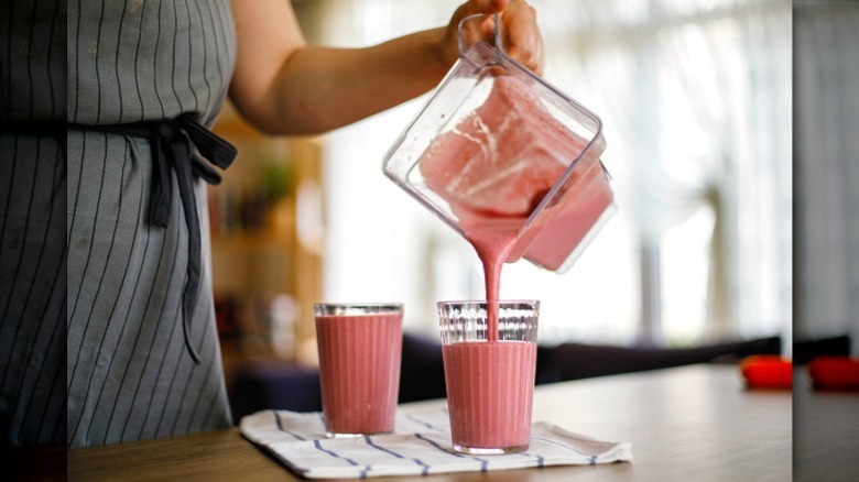 person pouring milkshake into two glasses