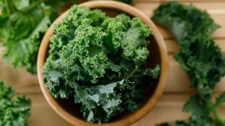 A wooden bowl full of kale.