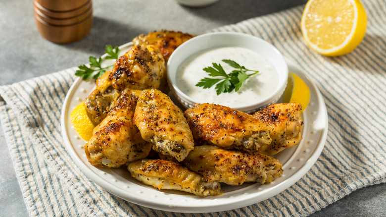 Lemon pepper wings on plate next to bowl of ranch sauce