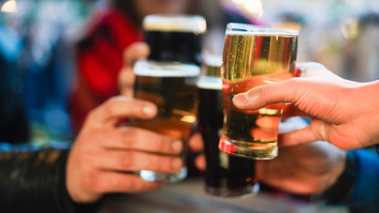 people clinking their beer glasses together at the pub