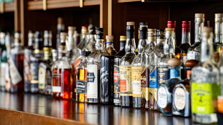 liquor bottles lined up on a shelf at a bar