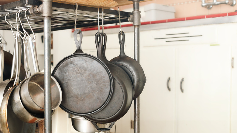 cast iron skillets hanging on a kitchen rack