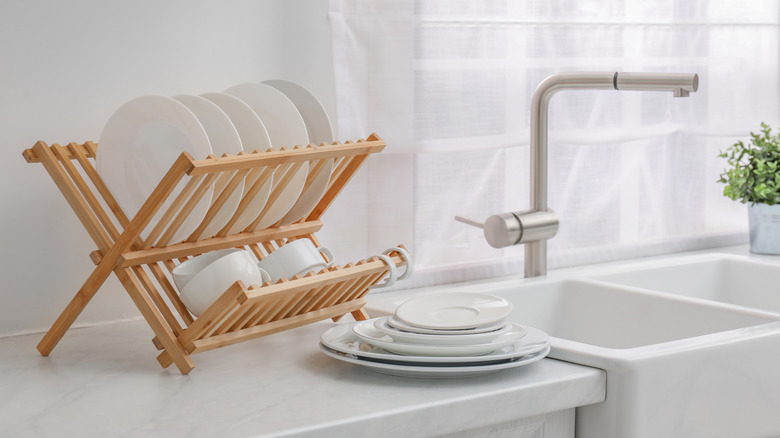 a folding wooden dish rack full of dishes on a white countertop