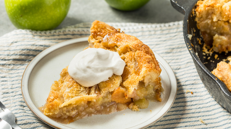 Slice of apple pie with whipped cream on a plate