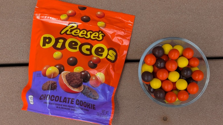 A top view of a bag of Reese's Pieces Chocolate Cookie and a bowl of candy pieces