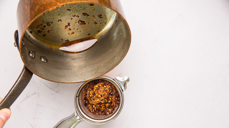 Straining oil from saucepan.