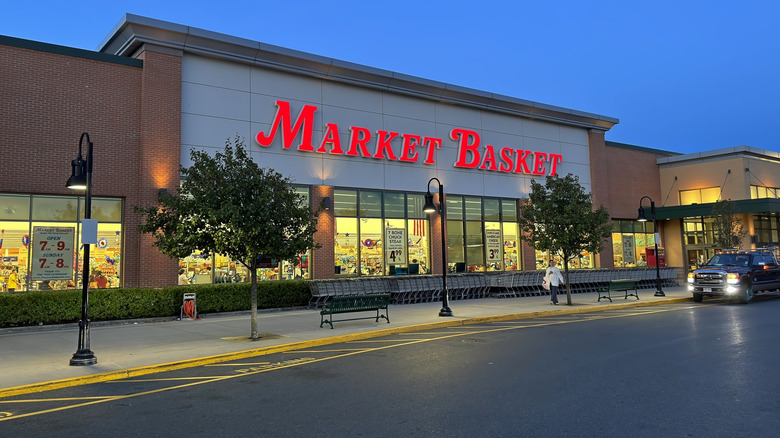 Market Basket exterior at night with a twilight sky behind it and parking lot in front