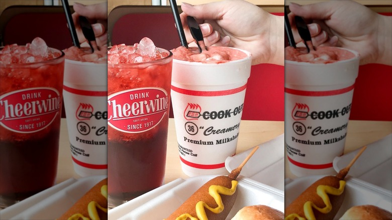 Corn dog in tray with Cheerwine and hand taking a spoonful from milkshake