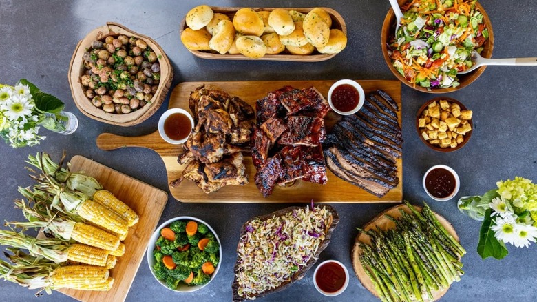 Aerial view of table filled with assorted smoked meats and sides incuding asparagus and corn