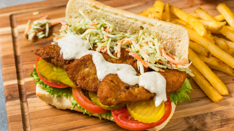 Fish po'boy on cutting board with fries