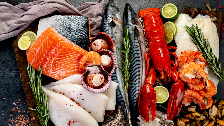 Array of raw seafood and seasoning, including white fish, shrimp, and lobster