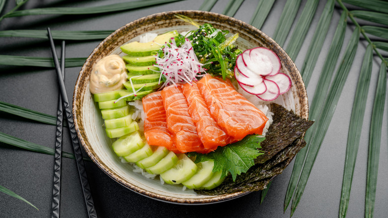 Poke bowl with raw salmon, radishes, cucumber, avocado, and nori
