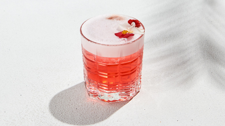 A pink fizz cocktail in a rocks glass