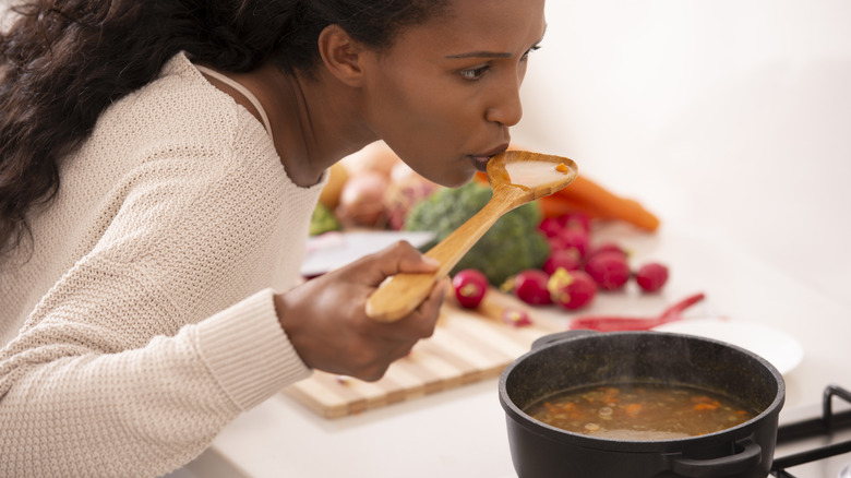 woman tasting food while cooking