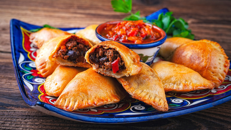 ground beef Empanadas on blue printed plate with salsa in bowl