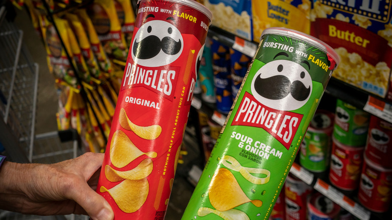 A shopper comparing two cans of Pringles chips