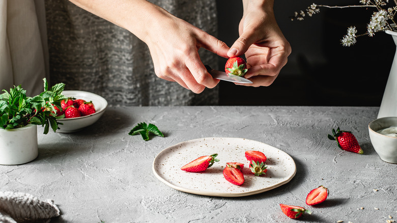 Hands cutting strawberries