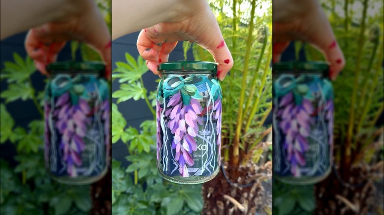 Hand holding painted jar outside