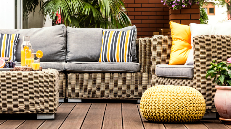 An outdoor couch and chairs with pillows and drinks