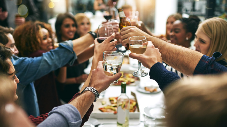 A large group of people at a restaurant table cheers their drinks.