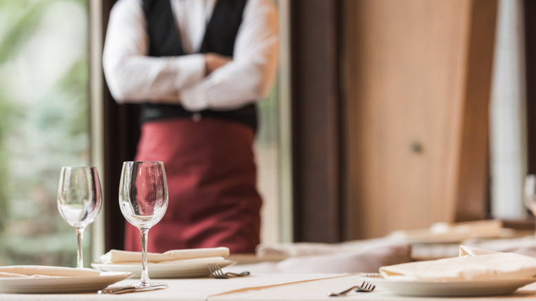 Restaurant staff member standing beside table