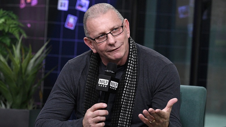 Robert Irvine speaking into a microphone and looking to the side