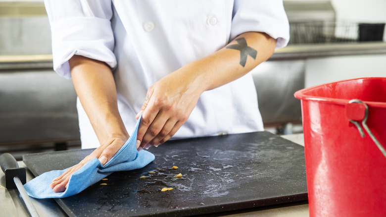 Chef wiping a cutting board with sanitizer