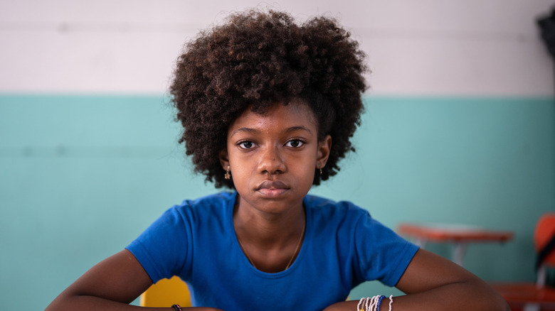 A teenage girl in a blue shirt staring blankly forward