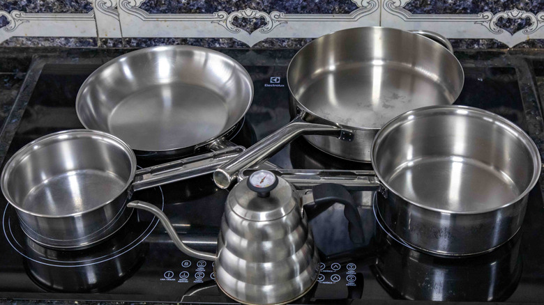 Shiny metal pans sit on a stove top.