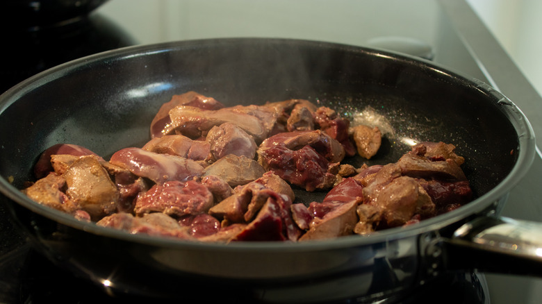 Close-up of frying liver in a black pan on a home stove