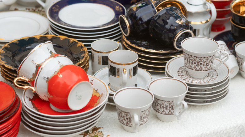 Stacks of vintage plates and teacups on table.