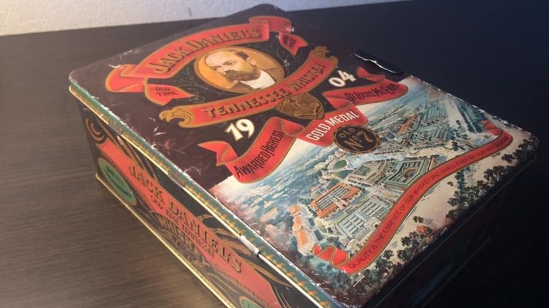 A Jack Daniel's 1904 Gold Medal gift set tin sitting on a dark wooden table