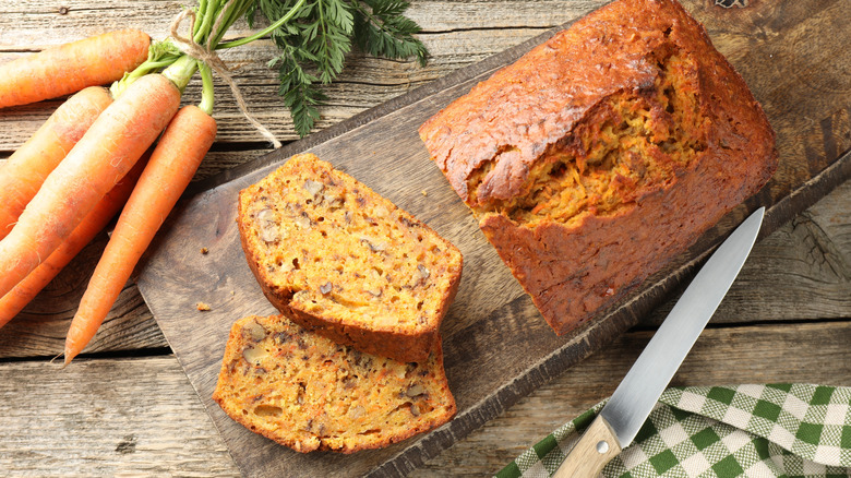 A sliced carrot loaf next to some whole carrots