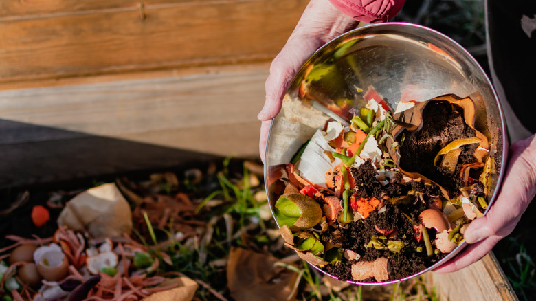 person tipping food waste with coffee grounds into compost area