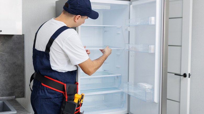 person working on refrigerator in kitchen