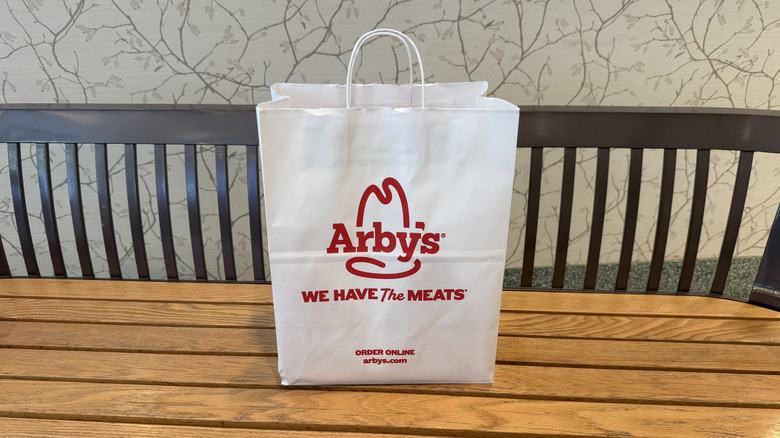 an Arby's bag on a bench