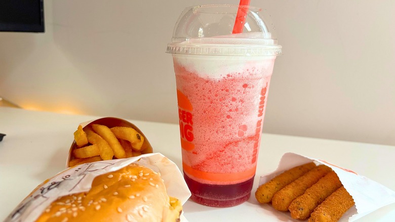 Burger King Frozen Strawberries & Cream on table with fries, mozzarella sticks, and part of a burger showing