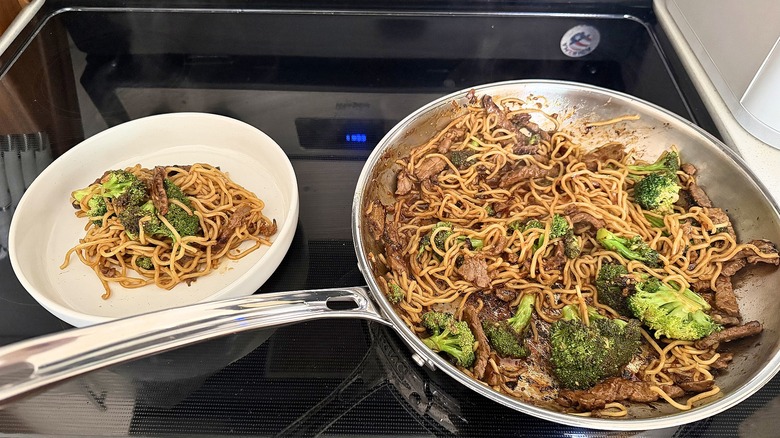 Plate of Costco beef and broccoli next to saute pan of the same beef and broccoli on stove
