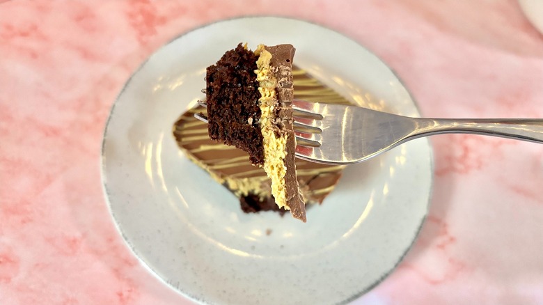 Piece of Crumbl Dubai Chocolate Brownie on fork over whole brownie on plate