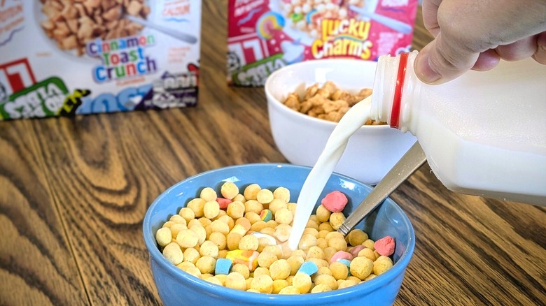 Milk being poured into a bowl of Ghost protein cereal with cereal boxes in the background