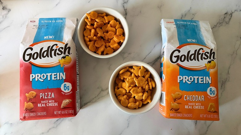 Two bags of Protein Goldfish on table with small white bowls of Goldfish between them, on marble surface