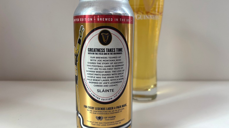 Back label of Guinness Legends Lager can in front of pint of Guinness on white table