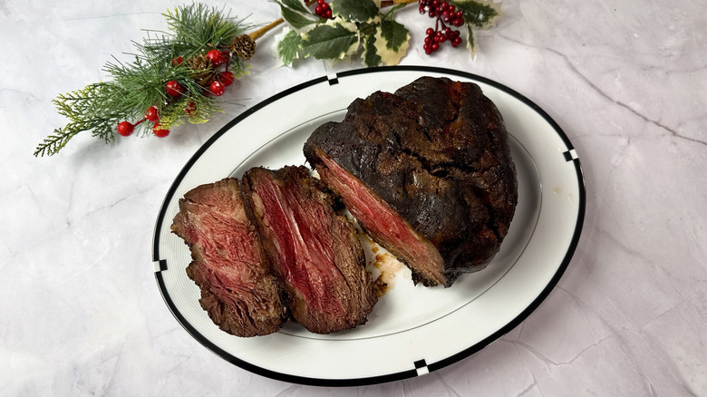 HoneyBaked prime rib on a serving platter with holly in the background