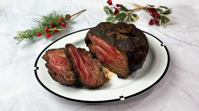 HoneyBaked prime rib on a serving plater with holly in the background